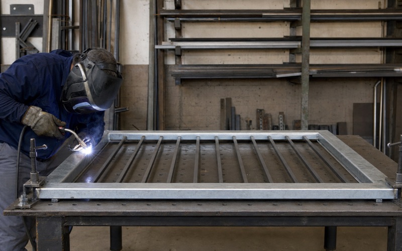Fabricator welding a corner joint on a gate frame in the shop
